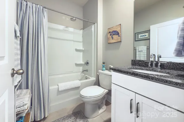 a bathroom with a granite countertop sink toilet a mirror a vanity and shower
