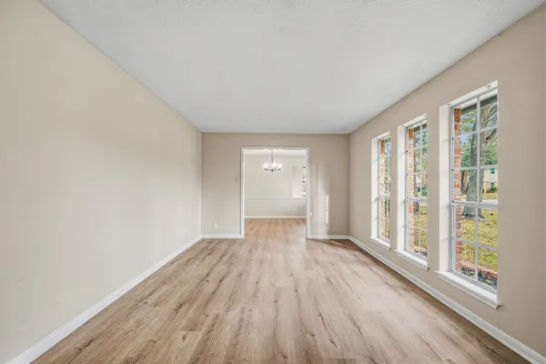 a view of an empty room with wooden floor and a window