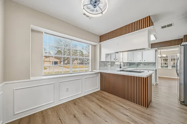 a kitchen with stainless steel appliances granite countertop a stove a sink and a white cabinets with wooden floor