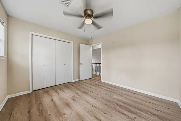 a view of an empty room with window and wooden floor