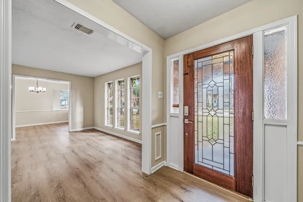 a view of an empty room with wooden floor and a window