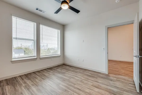 a view of an empty room with wooden floor and a window