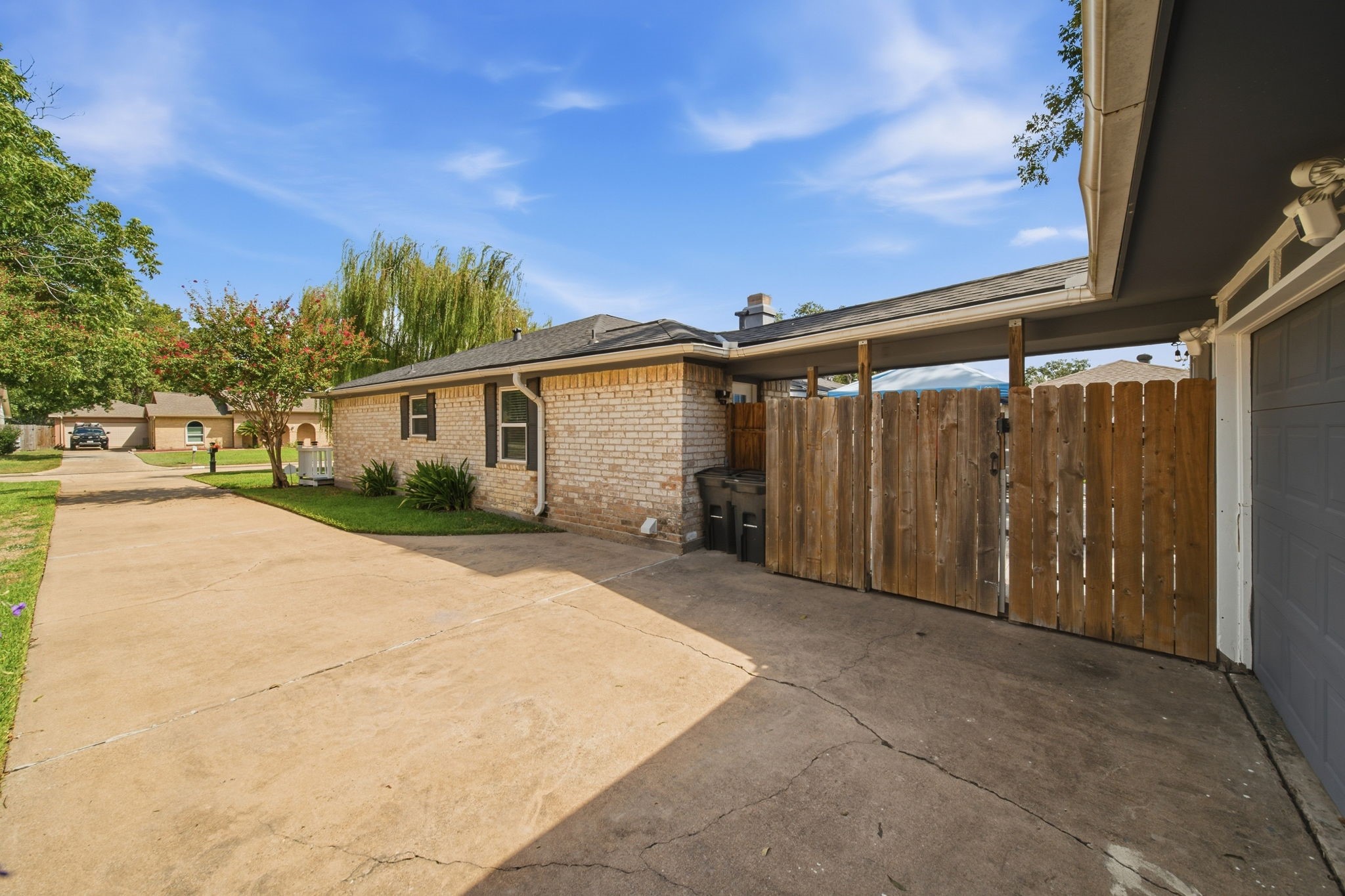 19519 Ricelake Lane Houston, TX 77084 - Photo 40 of 47 An abundantdriveway leads to a charming brick home with a gated wooden fence, offering privacy and ample parking.