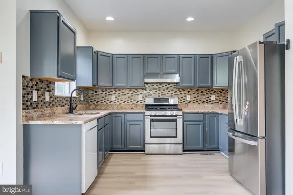 a kitchen with stainless steel appliances granite countertop a refrigerator sink and stove