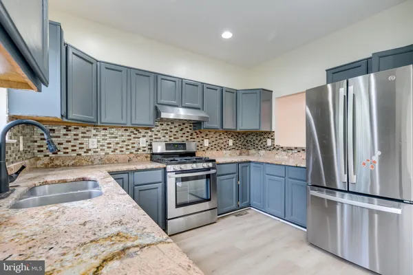 a kitchen with granite countertop a sink stove and refrigerator
