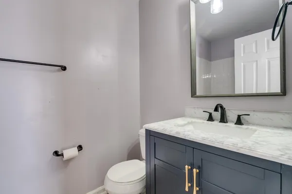 a bathroom with a granite countertop sink a toilet and mirror