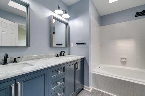 a bathroom with a sink double vanity granite tub and a mirror