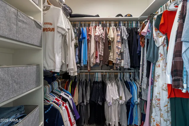 a view of walk in closet with clothes and shoes