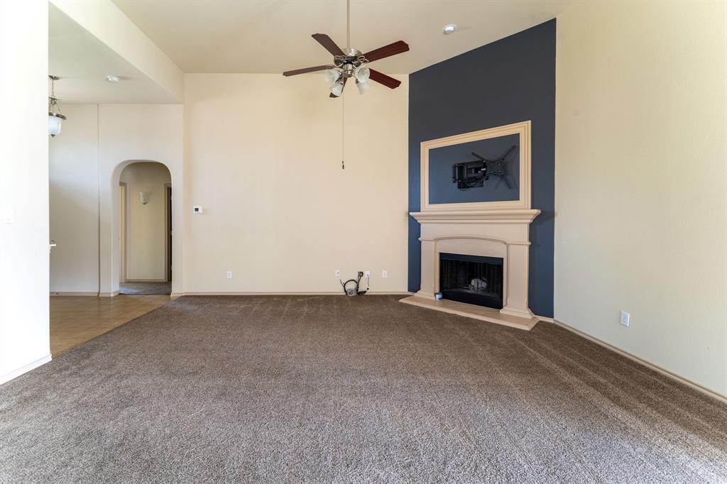 11156 Hawks Landing Road Fort Worth, TX 76052 - Photo 8 of 30 Spacious room with a fireplace featuring a decorative mantel, a ceiling fan, and carpet flooring