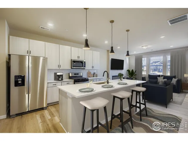 a kitchen with stainless steel appliances a table chairs refrigerator and microwave