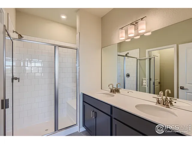 a bathroom with a double vanity sink mirror and shower