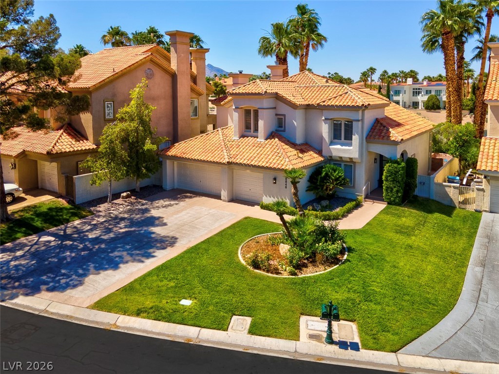 8848 Rainbow Ridge Drive Las Vegas, NV 89117 - Photo 42 of 43 A well-maintained lawn and mature landscaping enhance this Mediterranean-inspired residence, featuring a tile roof and attached garages.