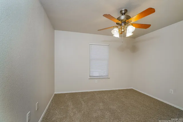 an empty room with a chandelier fan and a window