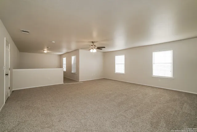 an empty room with windows and ceiling fan view