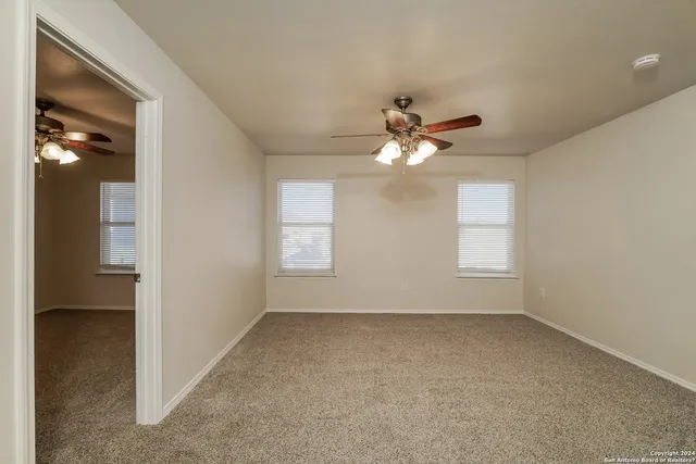 an empty room with a chandelier fan and windows