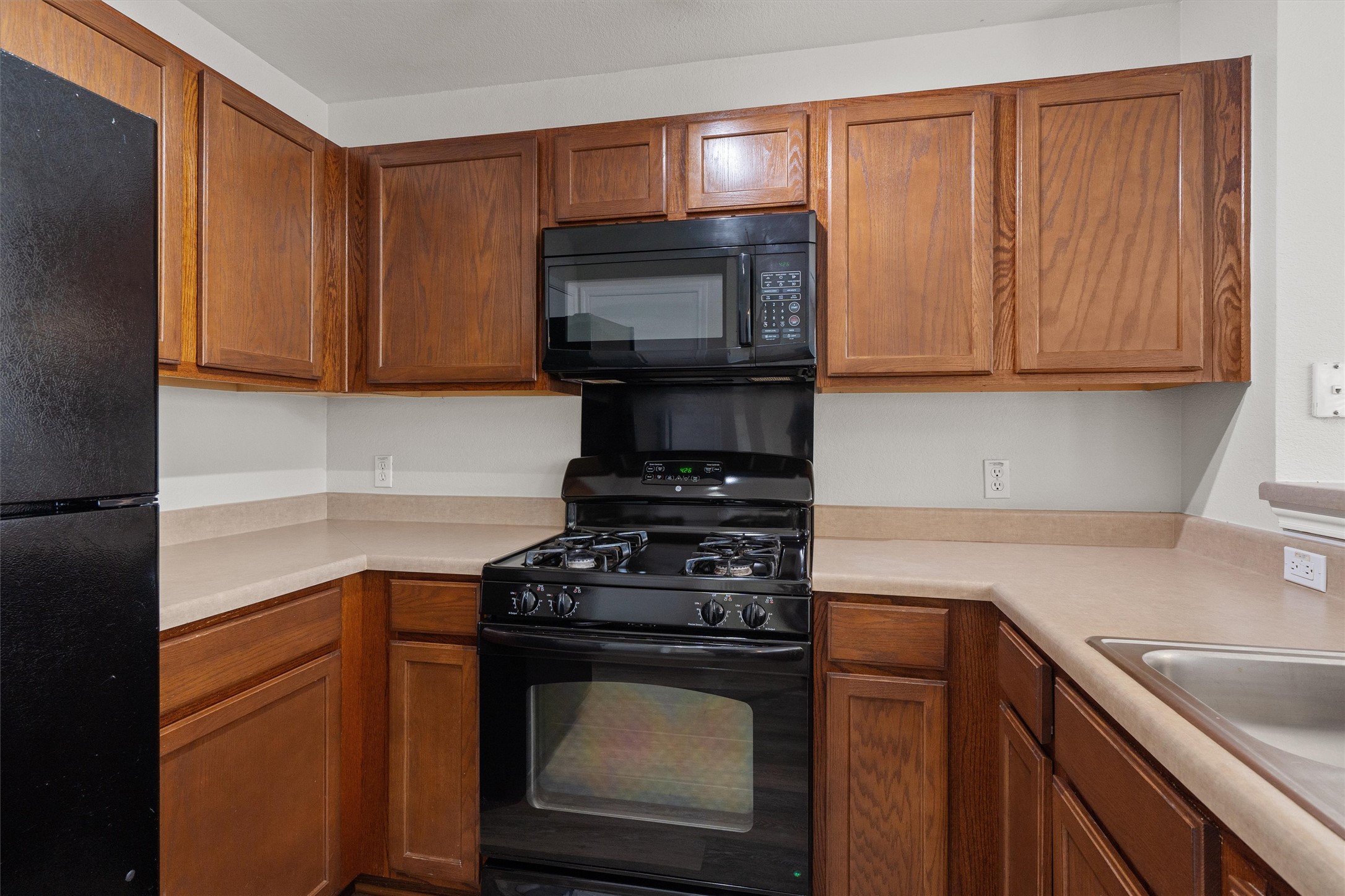 5825 Silver Screen Drive Austin, TX 78747 - Photo 12 of 40 A well-appointed kitchen showcasing rich wooden cabinetry and contemporary black appliances.