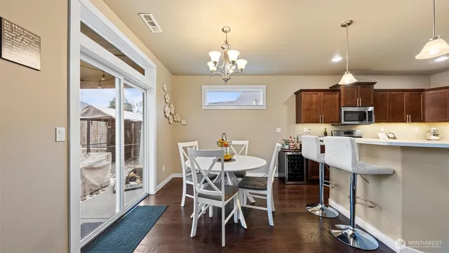 a kitchen with stainless steel appliances kitchen island granite countertop a dining table chairs and a refrigerator