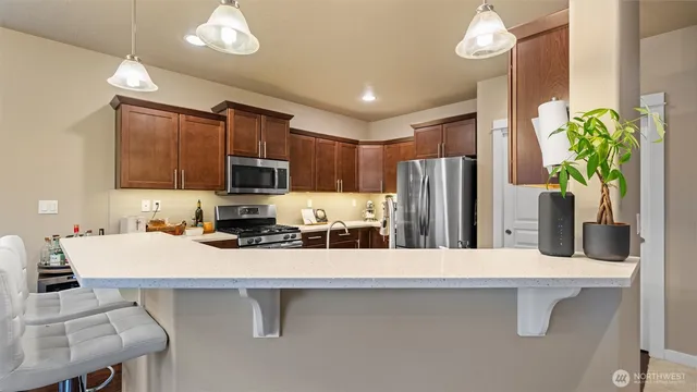 a kitchen with stainless steel appliances a sink a stove a refrigerator cabinets and chairs