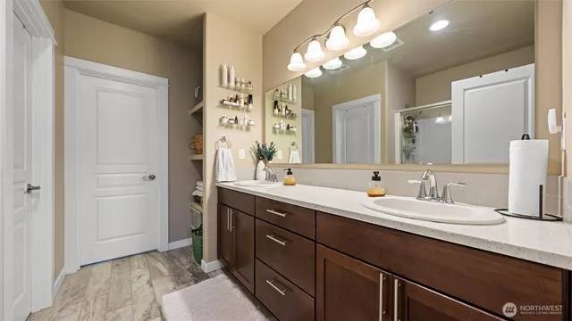 a spacious bathroom with a double vanity sink a mirror and a shower