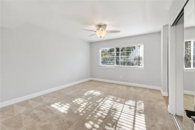 an empty room with windows and ceiling fan