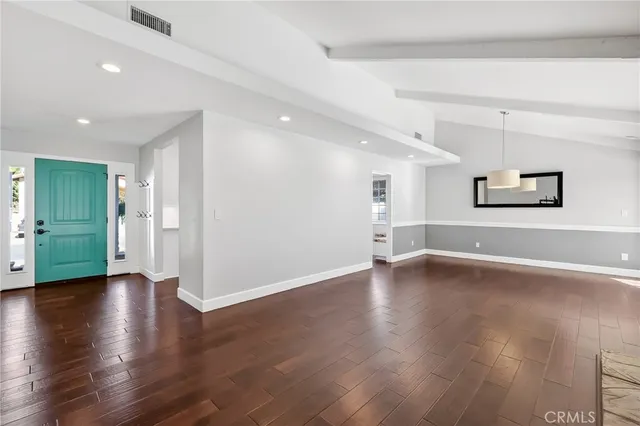 a view of a big room with wooden floor and windows