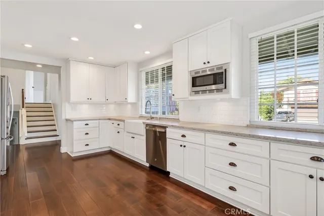 a kitchen with white cabinets stainless steel appliances and a window