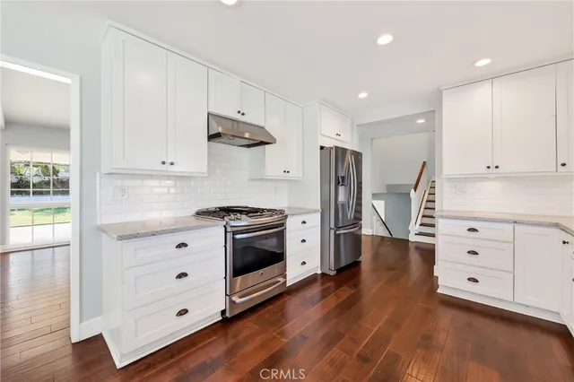 a kitchen with stainless steel appliances a stove refrigerator and cabinets