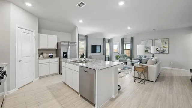 a kitchen with stainless steel appliances a dining table chairs refrigerator and sink