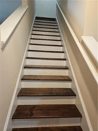 a view of empty room with wooden floor and kitchen view