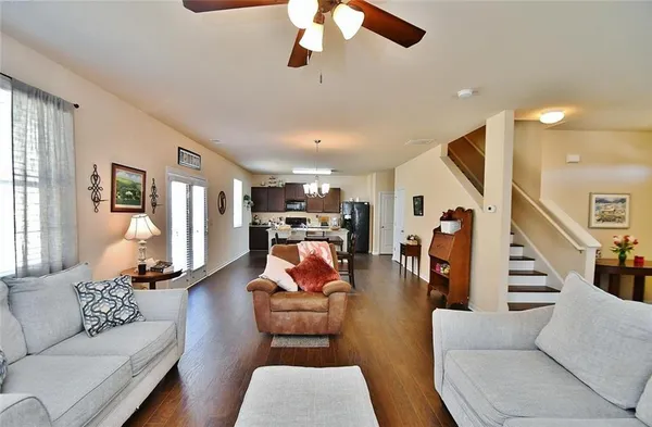 a living room with furniture kitchen view and a wooden floor