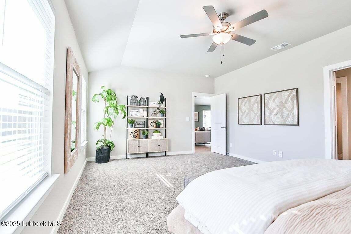 324 Ranger Street Wolfforth, TX 79382 - Photo 5 of 12 a spacious bedroom with a large bed a chandelier and a large window