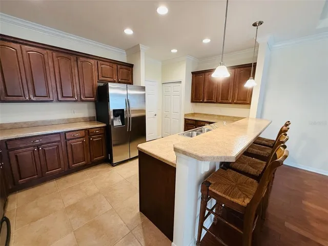 a kitchen with a refrigerator a stove top oven a sink with island and chairs