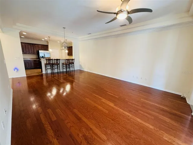 a view of empty room with kitchen view and wooden floor