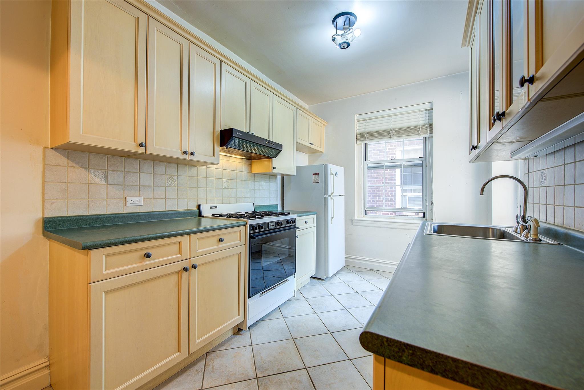 117-01 Park Lane South, Unit C5D Queens, NY 11418 - Photo 14 of 33 a kitchen with granite countertop a sink a stove and cabinets