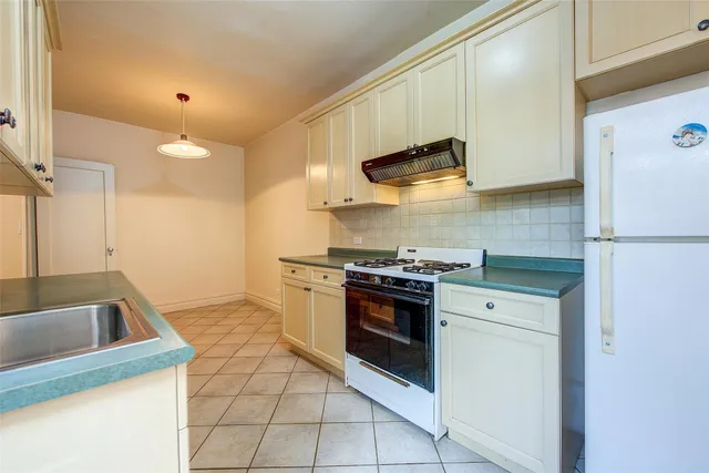 a kitchen with stainless steel appliances granite countertop a sink a stove a refrigerator and a white cabinets