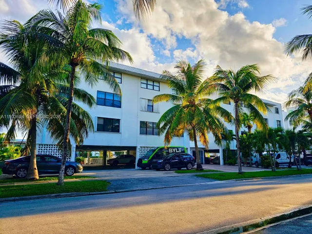 a front view of multi story residential apartment building with yard and sign board