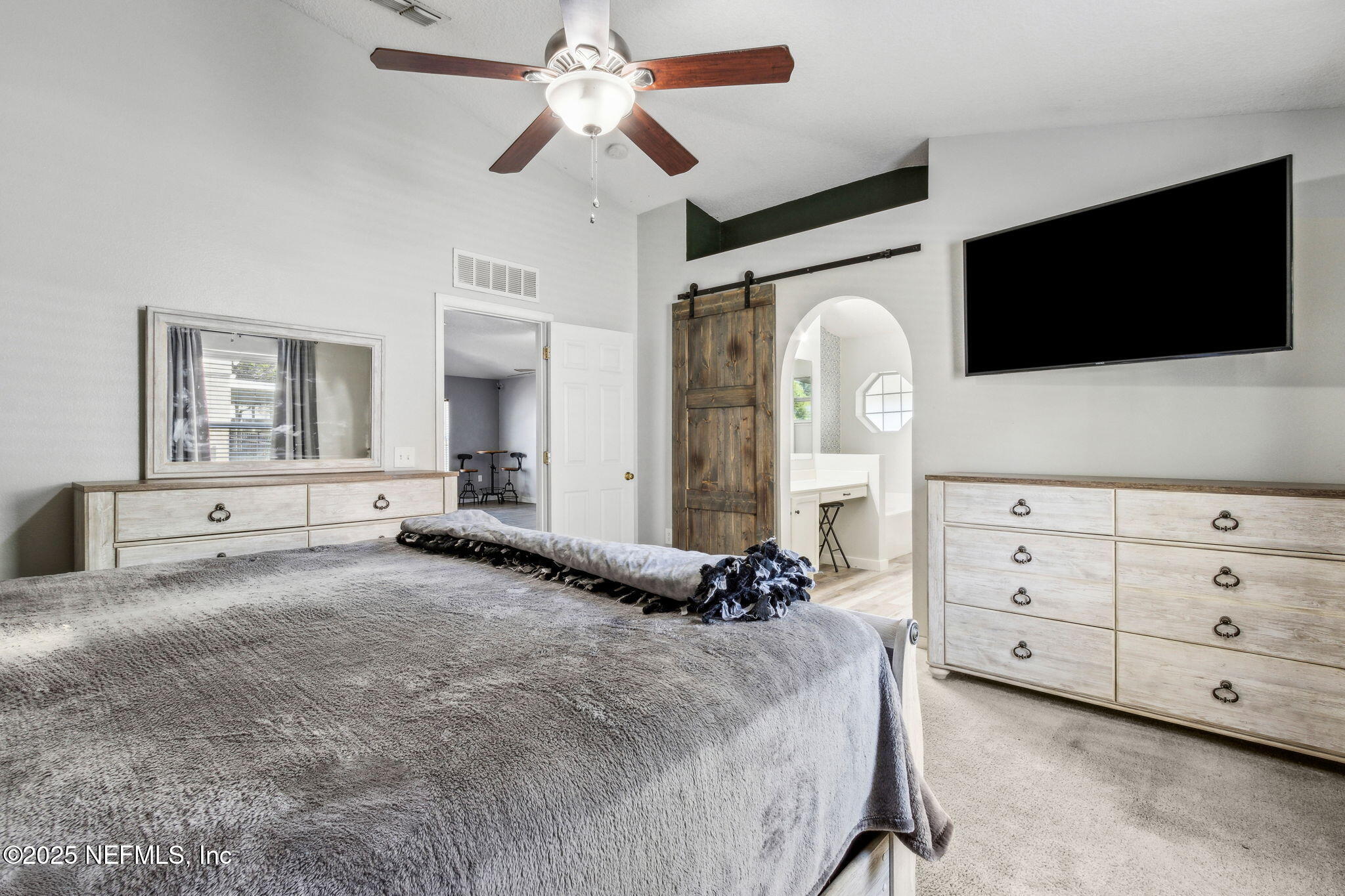 76564 Longleaf Loop Yulee, FL 32097 - Photo 31 of 54 a spacious bedroom with a bed a mirror on dresser and a flat screen tv