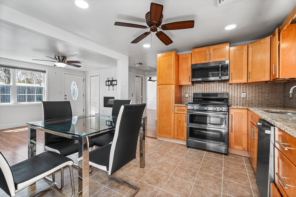 32 Shaw Road Brockton, MA 02301 - Photo 9 of 27 a kitchen with stainless steel appliances kitchen island granite countertop a stove top oven a sink a dining table and chairs with wooden floor