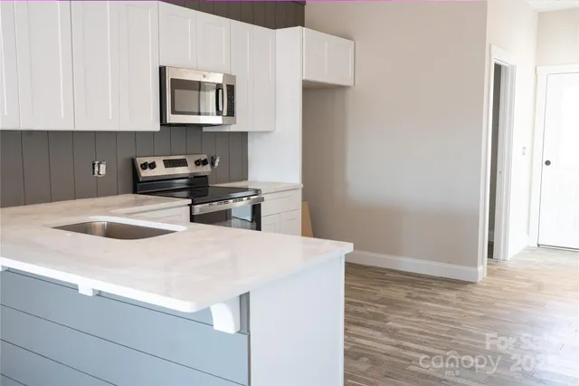 a kitchen with granite countertop a stove a microwave and a refrigerator