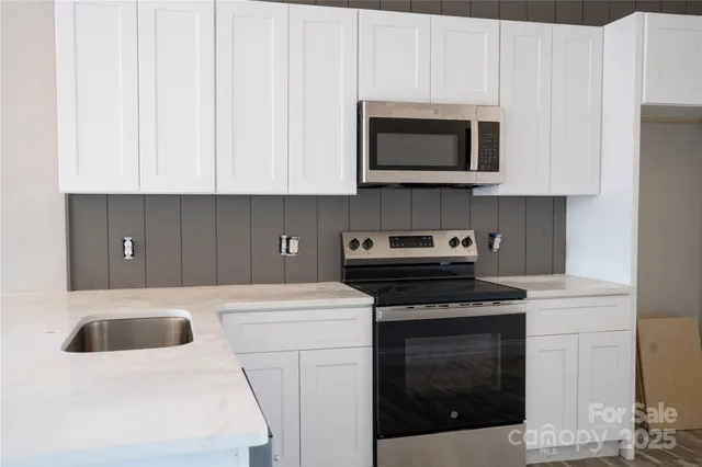 a kitchen with stainless steel appliances a stove a microwave and white cabinets