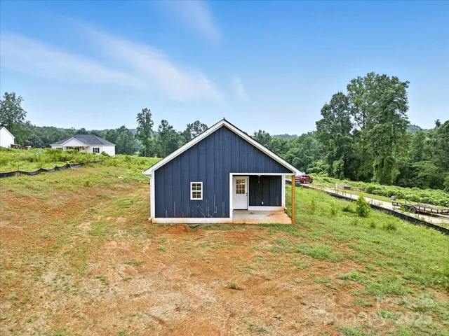 a view of a house with yard and trees in the background