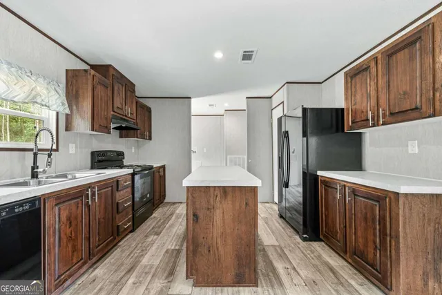 a kitchen with stainless steel appliances a sink cabinets and wooden floor