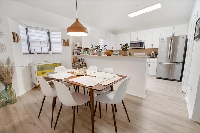 a kitchen with stainless steel appliances a dining table chairs and a refrigerator