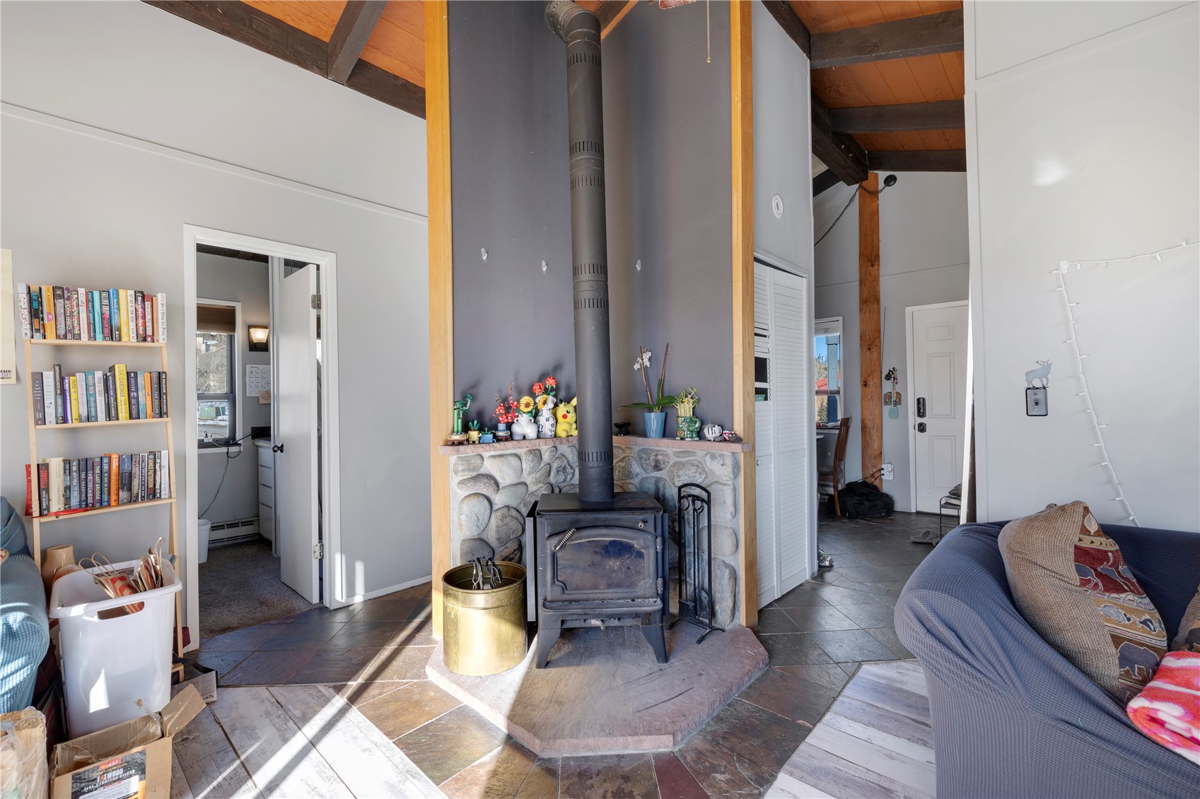 809 Ryan Gulch Road, Unit 809 Silverthorne, CO 80498 - Photo 13 of 17 Living area with a wood stove, stone tile floors, and a high wooden beamed ceiling