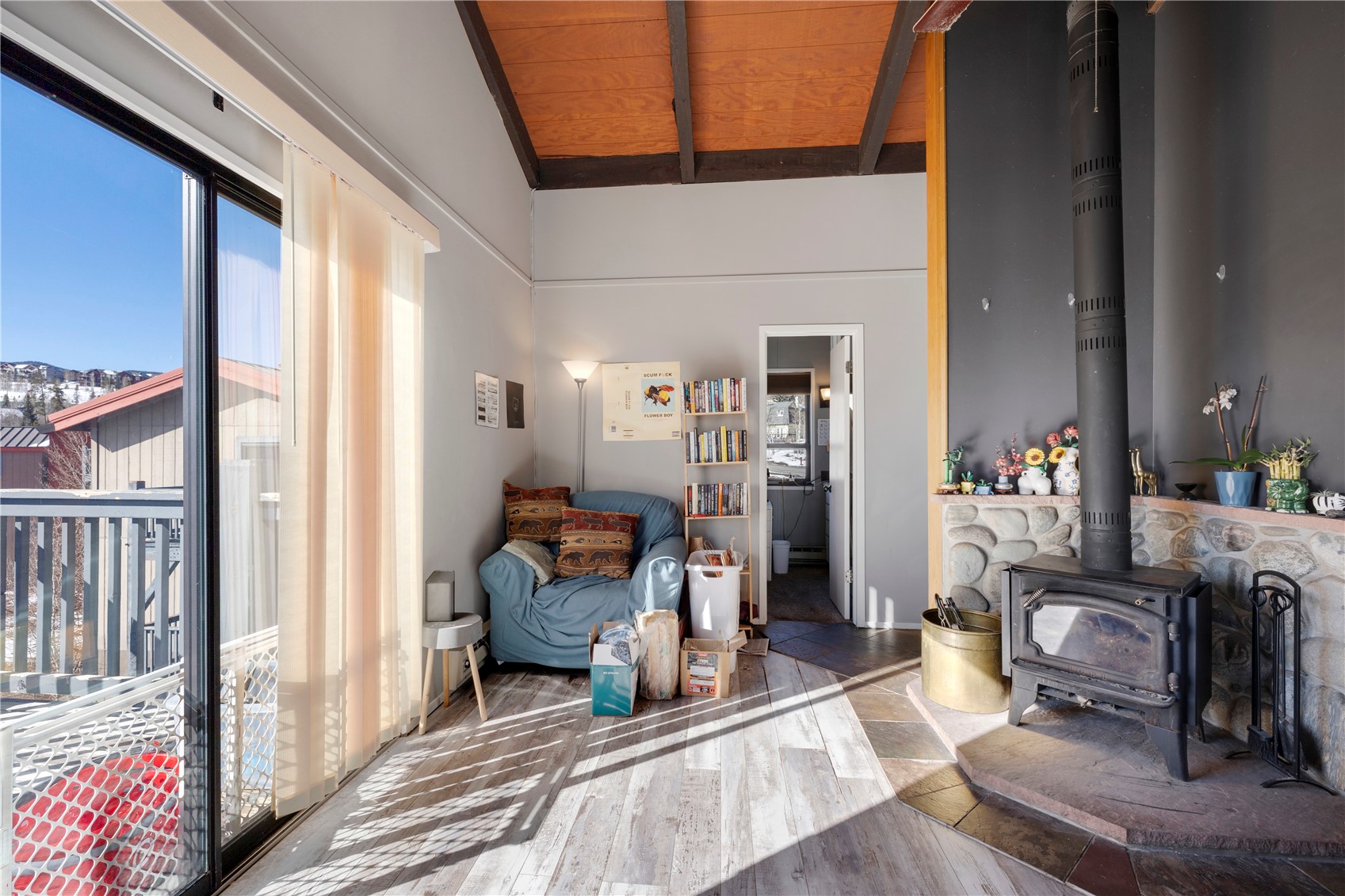 809 Ryan Gulch Road, Unit 809 Silverthorne, CO 80498 - Photo 7 of 17 Living area featuring a wood stove, wood finished floors, wood ceiling, and vaulted ceiling with beams