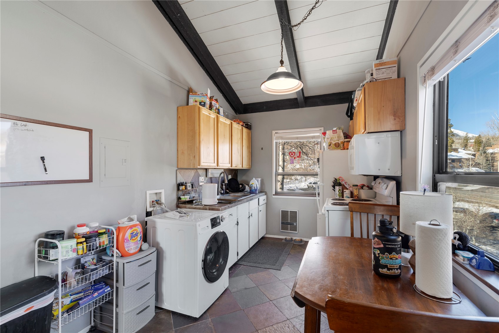 809 Ryan Gulch Road, Unit 809 Silverthorne, CO 80498 - Photo 10 of 17 Kitchen with washer / dryer, white appliances, vaulted ceiling with beams, wood ceiling, and light wood finish cabinets