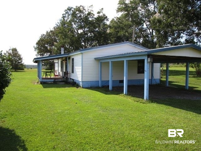 20705 Greek Cemetery Road Robertsdale, AL 36567 - Photo 6 of 25 View of side of home featuring a lawn, a wooden deck, and an attached carport