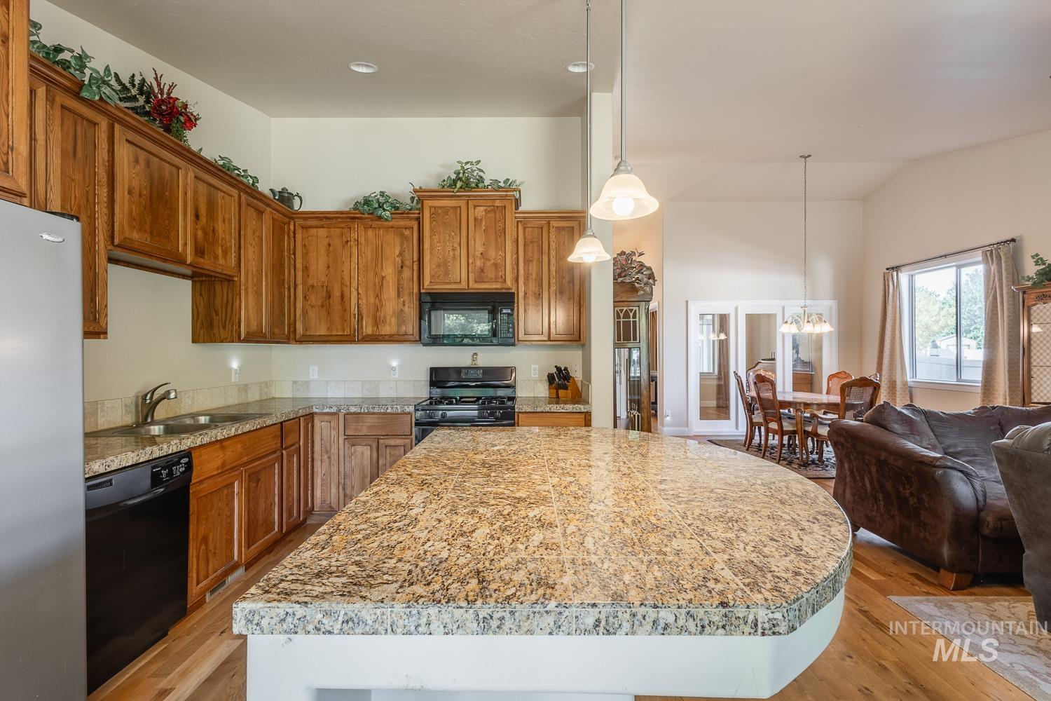 1186 East Observation Street Meridian, ID 83642 - Photo 15 of 33 Kitchen featuring a large curved island with granite-style countertop, abundant wood cabinetry, and stainless steel appliances