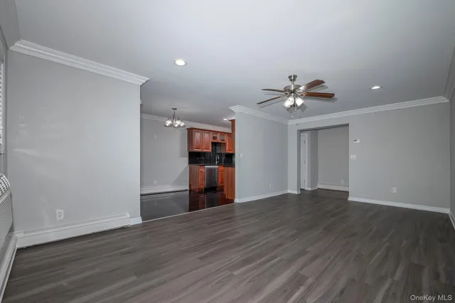 a view of an empty room with wooden floor and a ceiling fan