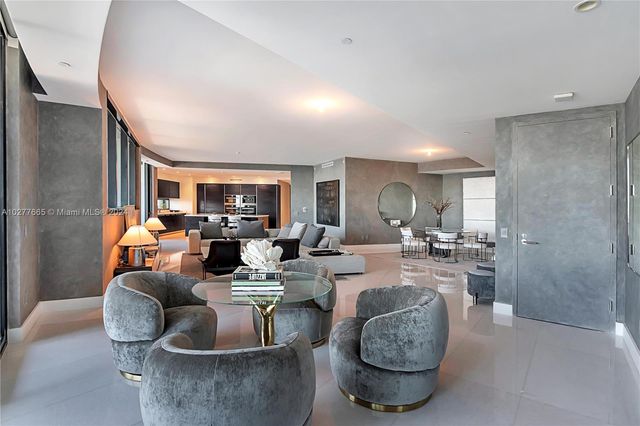 a living room with furniture potted plant and kitchen view